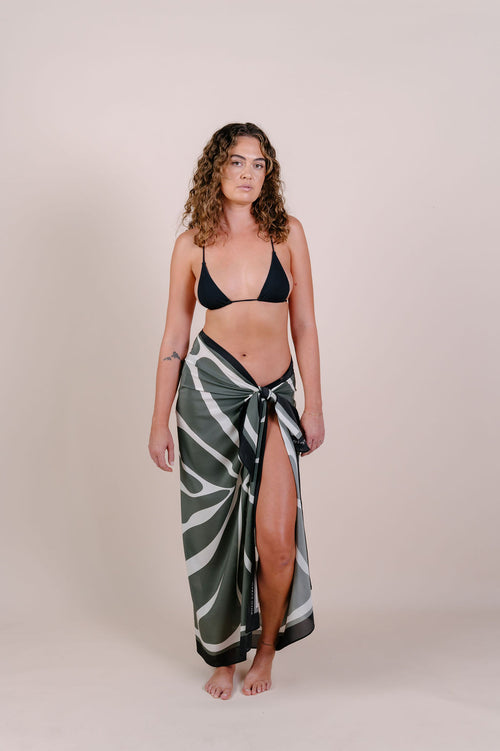 Model wearing the Camille olive abstract silk pareo by Novo Pareo. 100% Mulberry Silk Twill with flowing organic lines, designed in Australia for effortless, refined resort wear versatility.
