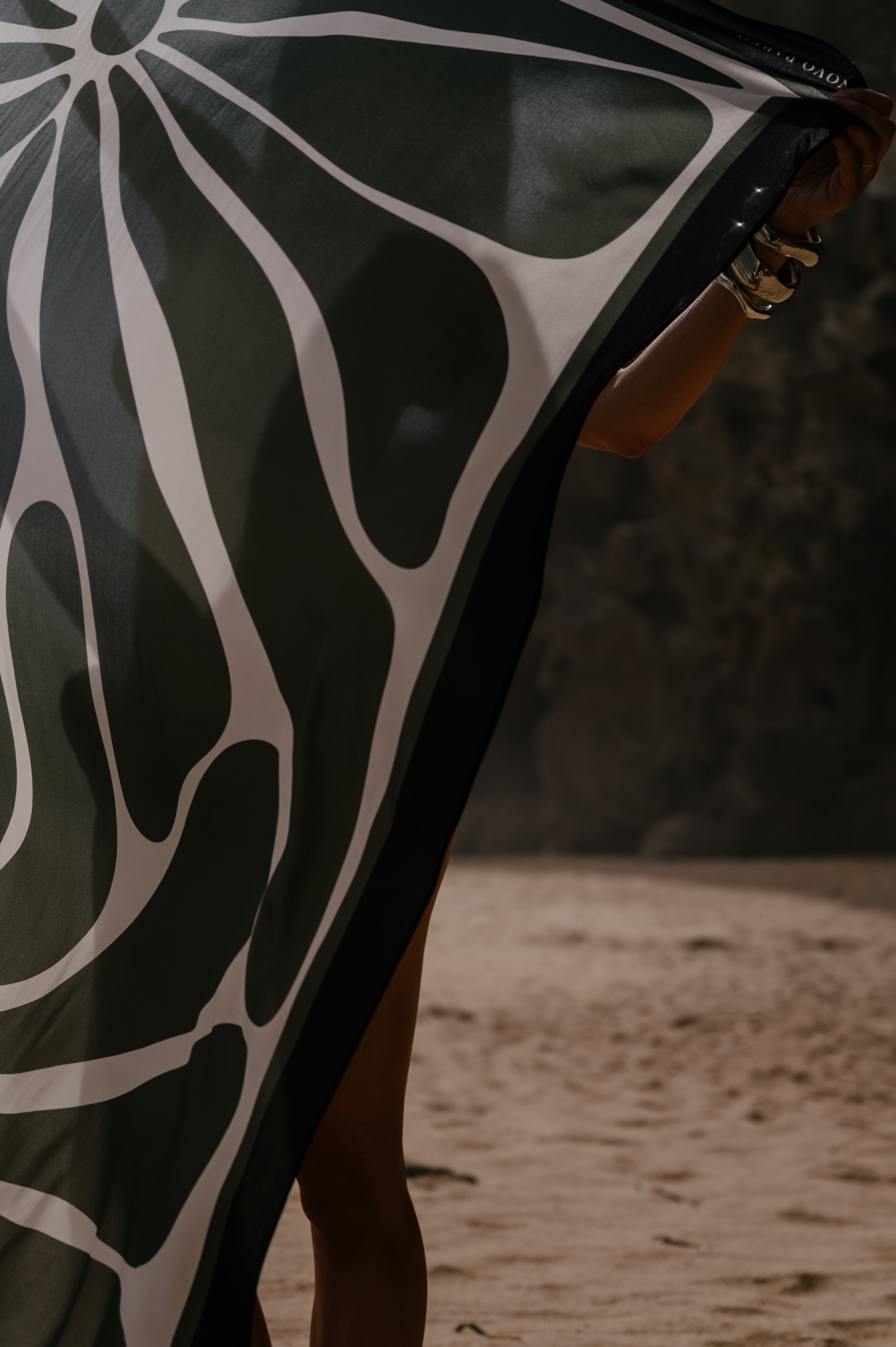 Model with a black and white patterned pareo sarong on a sandy background