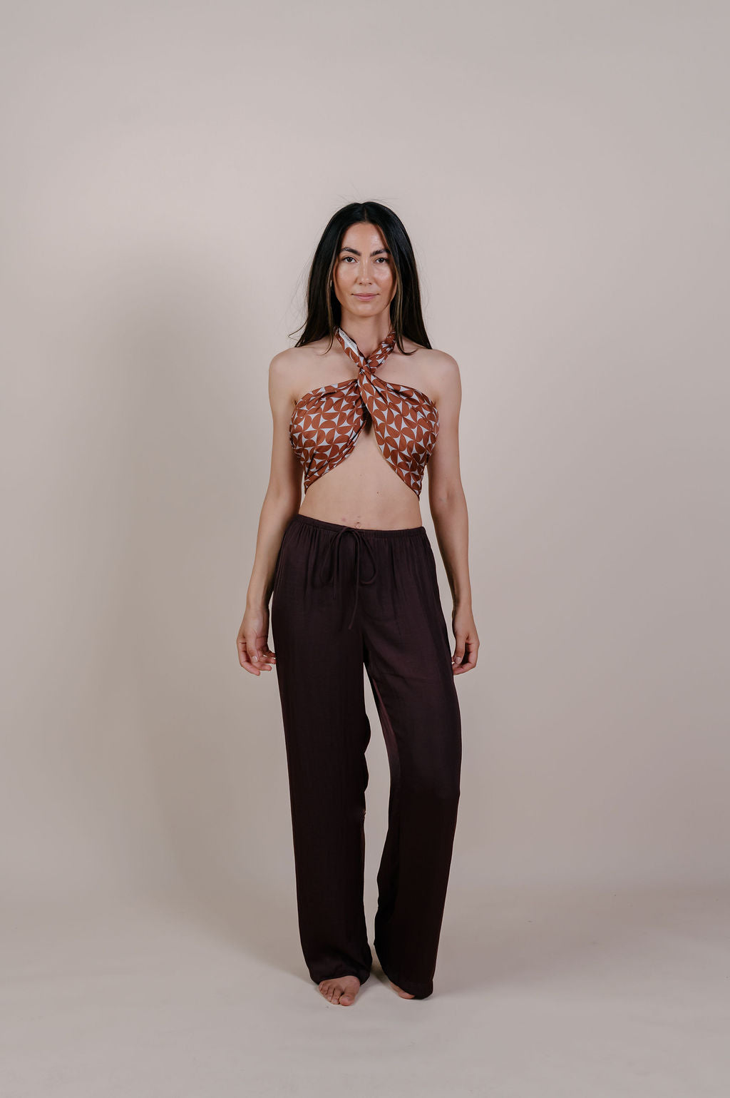 Model wearing the Celine caramel geometric silk pareo by Novo Pareo. 100% Mulberry Silk Twill with a rich caramel and ivory pattern, reflecting timeless elegance and Australian refined resort wear.