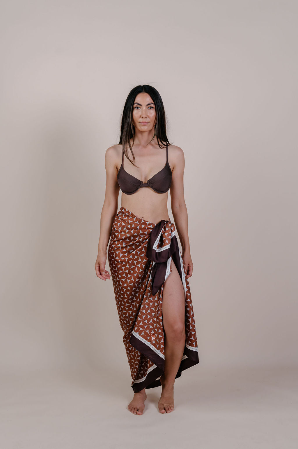 Model wearing the Celine caramel geometric silk pareo by Novo Pareo. 100% Mulberry Silk Twill with a rich caramel and ivory pattern, reflecting timeless elegance and Australian refined resort wear.