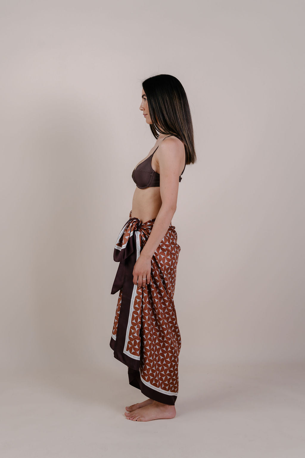 Model wearing the Celine caramel geometric silk pareo by Novo Pareo. 100% Mulberry Silk Twill with a rich caramel and ivory pattern, reflecting timeless elegance and Australian refined resort wear.