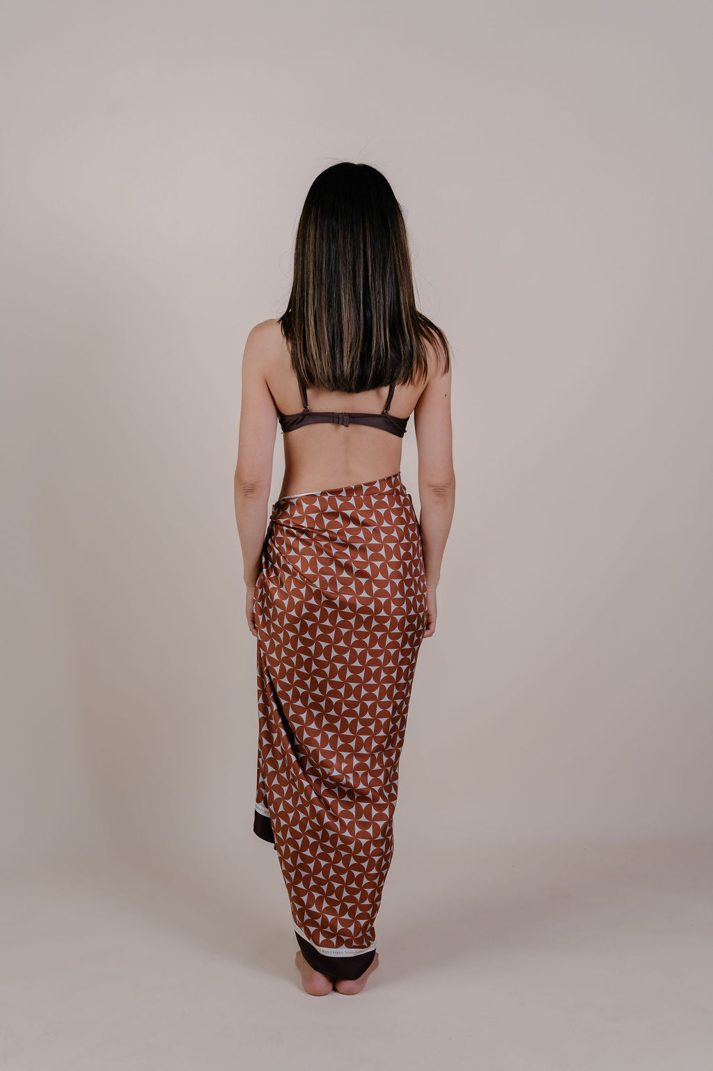 Model wearing the Celine caramel geometric silk pareo by Novo Pareo. 100% Mulberry Silk Twill with a rich caramel and ivory pattern, reflecting timeless elegance and Australian refined resort wear.