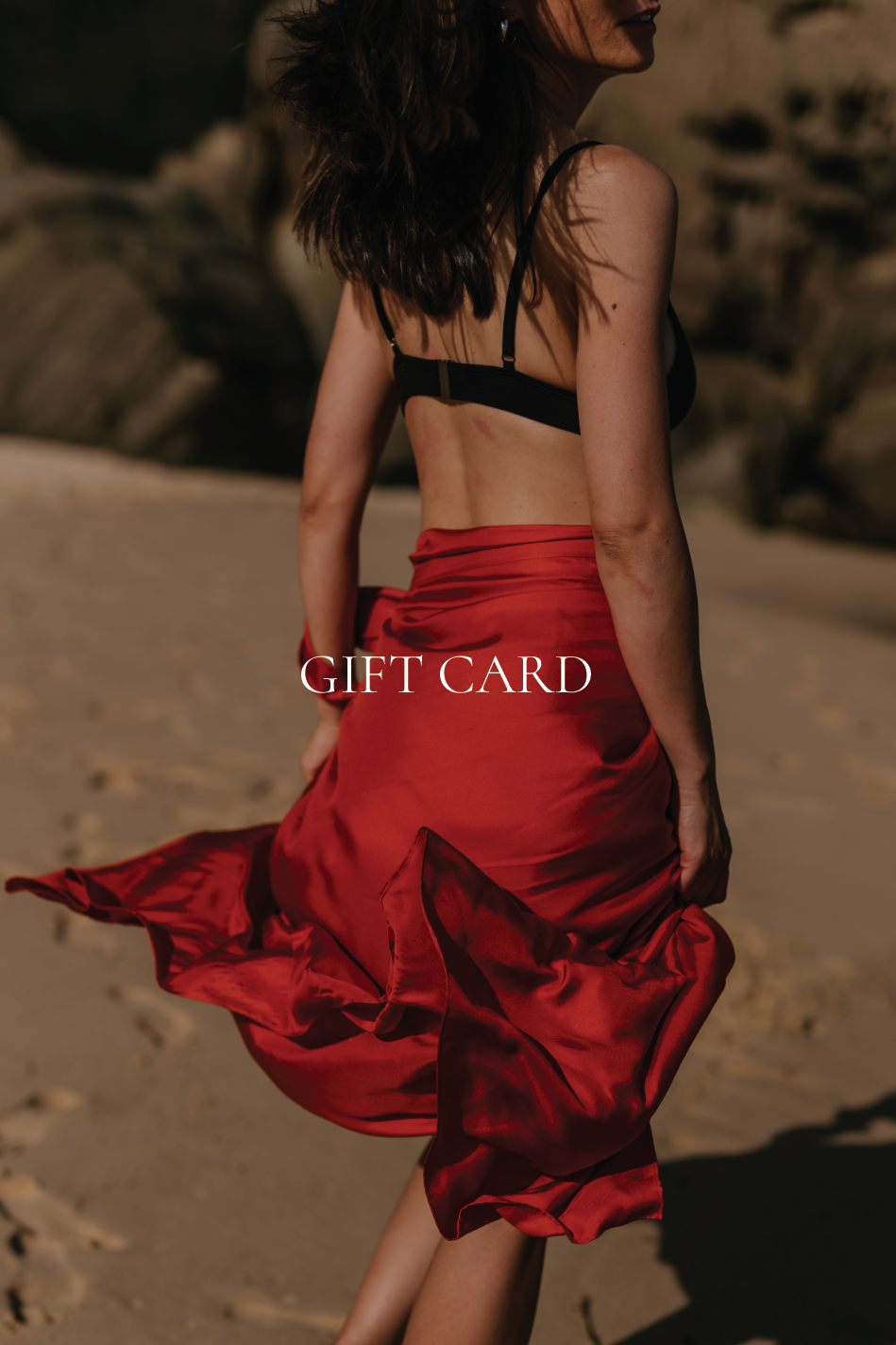 Novo Pareo 100% silk pareo styled as a skirt in rich red, worn on the beach to showcase luxury Australian resort wear and beach-to-beyond styling