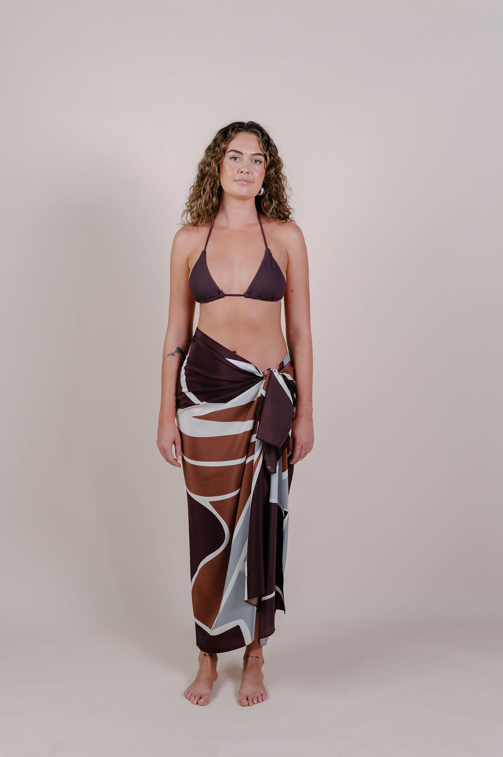 Model wearing the Isla flow print silk pareo by Novo Pareo. Elegant abstract design in deep chocolate and soft grey, crafted from 100% Mulberry Silk Twill for effortless, versatile resort wear.