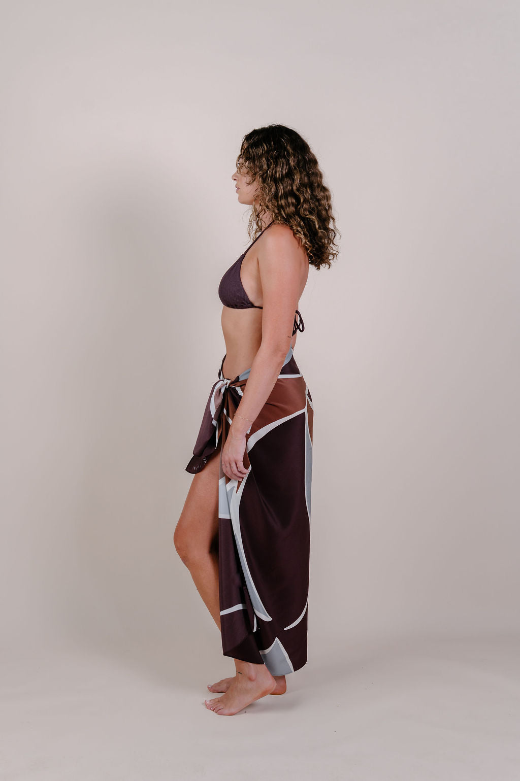 Model wearing the Isla flow print silk pareo by Novo Pareo. Elegant abstract design in deep chocolate and soft grey, crafted from 100% Mulberry Silk Twill for effortless, versatile resort wear.