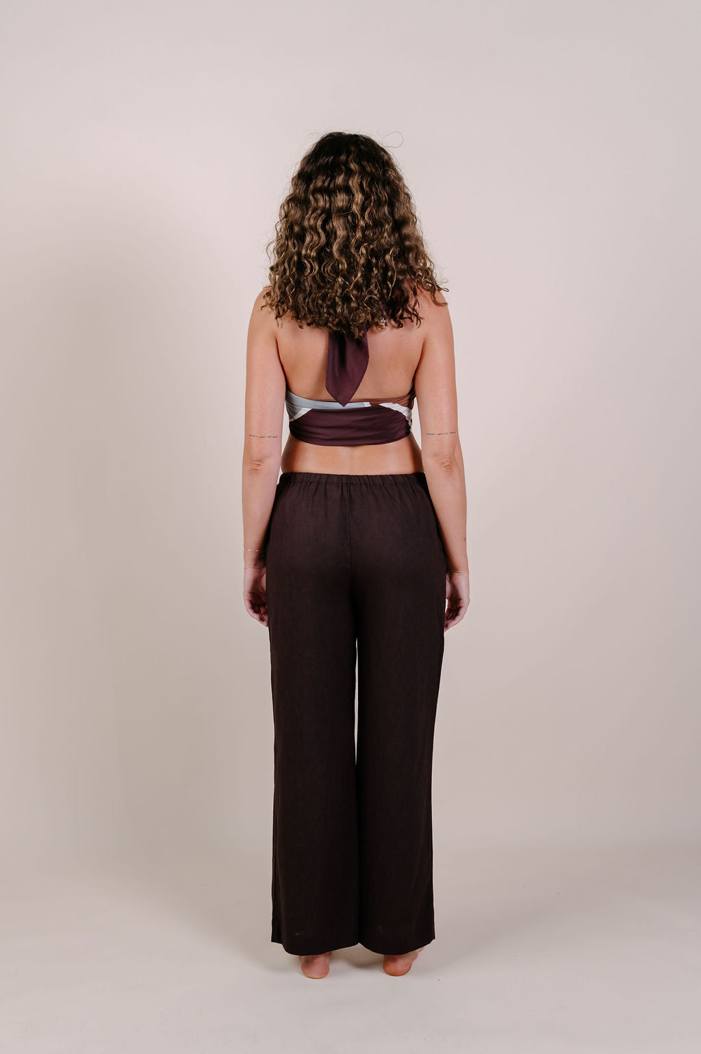 Model wearing the Isla flow print silk pareo by Novo Pareo. Elegant abstract design in deep chocolate and soft grey, crafted from 100% Mulberry Silk Twill for effortless, versatile resort wear.