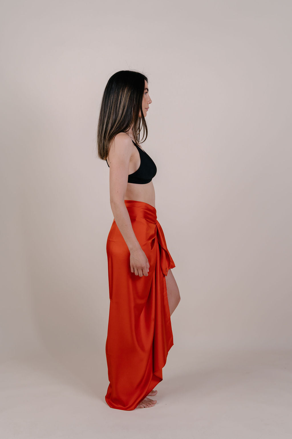 Model wearing the Luana solid terracotta silk pareo by Novo Pareo. Made from 100% Mulberry Silk Twill in warm terracotta, a timeless and versatile piece for refined Australian resort wear.