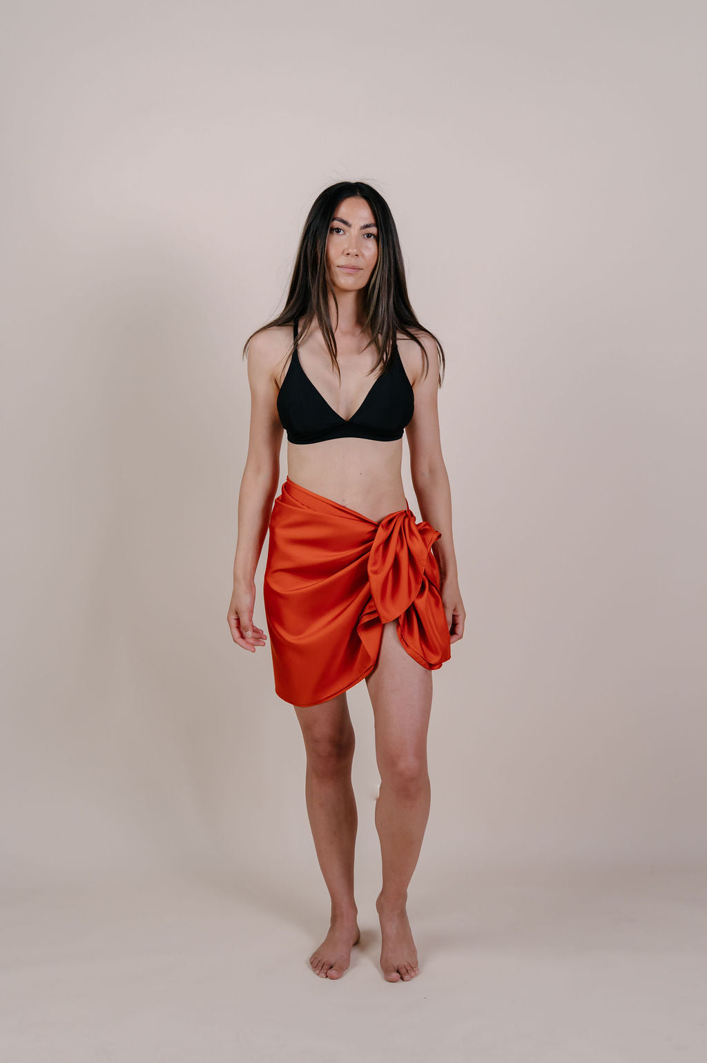 Model wearing the Luana solid terracotta silk pareo by Novo Pareo. Made from 100% Mulberry Silk Twill in warm terracotta, a timeless and versatile piece for refined Australian resort wear.