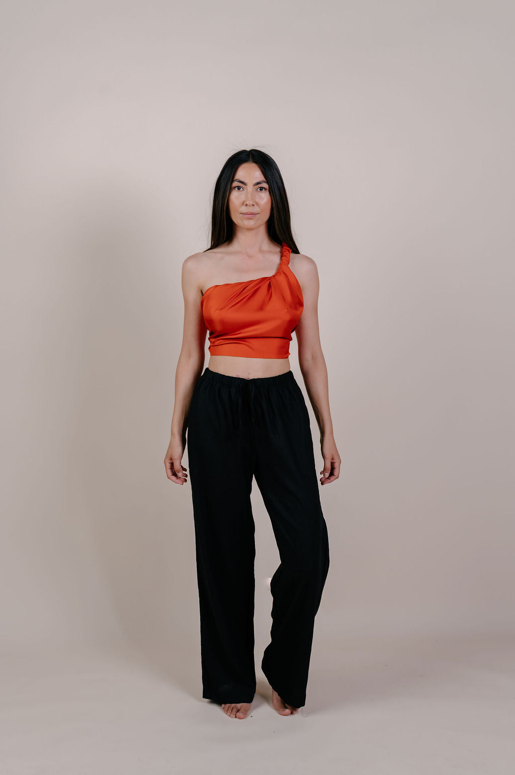 Model wearing the Luana solid terracotta silk pareo by Novo Pareo. Made from 100% Mulberry Silk Twill in warm terracotta, a timeless and versatile piece for refined Australian resort wear.