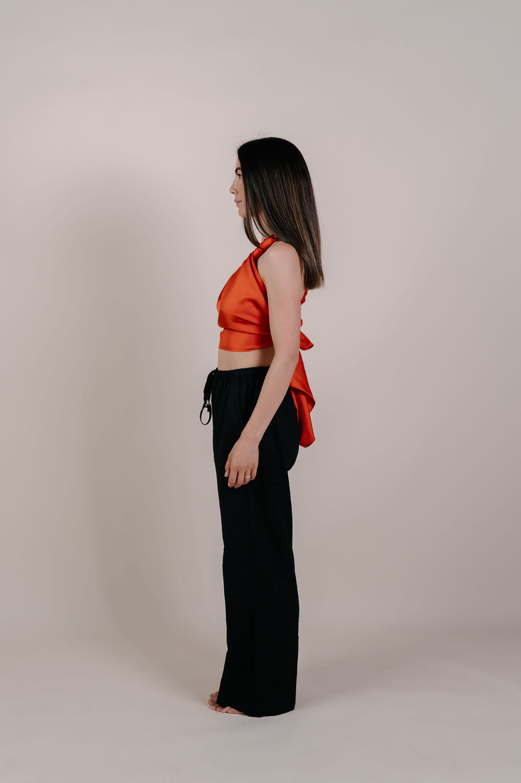 Model wearing the Luana solid terracotta silk pareo by Novo Pareo. Made from 100% Mulberry Silk Twill in warm terracotta, a timeless and versatile piece for refined Australian resort wear.