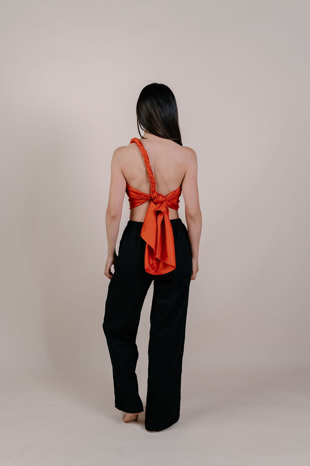 Model wearing the Luana solid terracotta silk pareo by Novo Pareo. Made from 100% Mulberry Silk Twill in warm terracotta, a timeless and versatile piece for refined Australian resort wear.