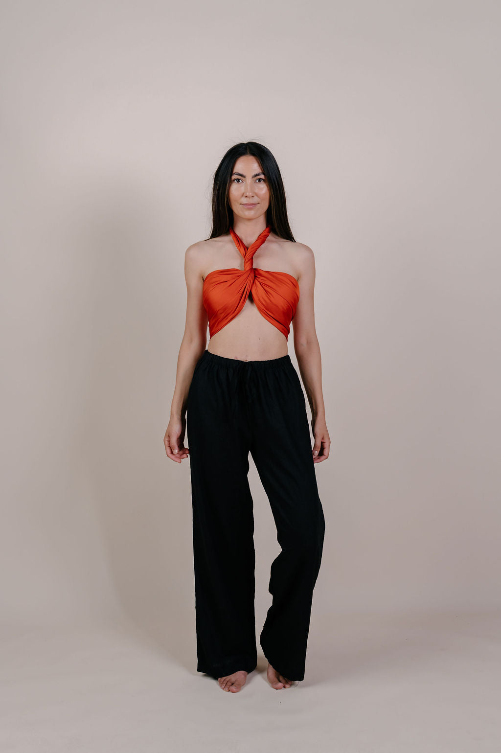 Model wearing the Luana solid terracotta silk pareo by Novo Pareo. Made from 100% Mulberry Silk Twill in warm terracotta, a timeless and versatile piece for refined Australian resort wear.