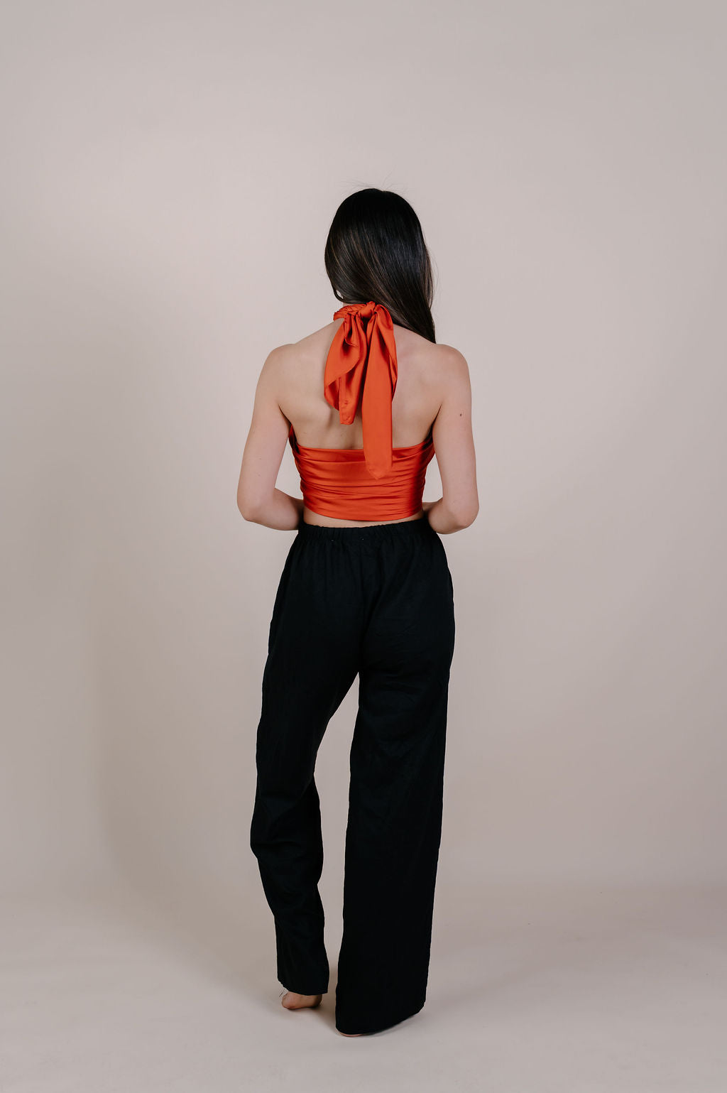 Model wearing the Luana solid terracotta silk pareo by Novo Pareo. Made from 100% Mulberry Silk Twill in warm terracotta, a timeless and versatile piece for refined Australian resort wear.