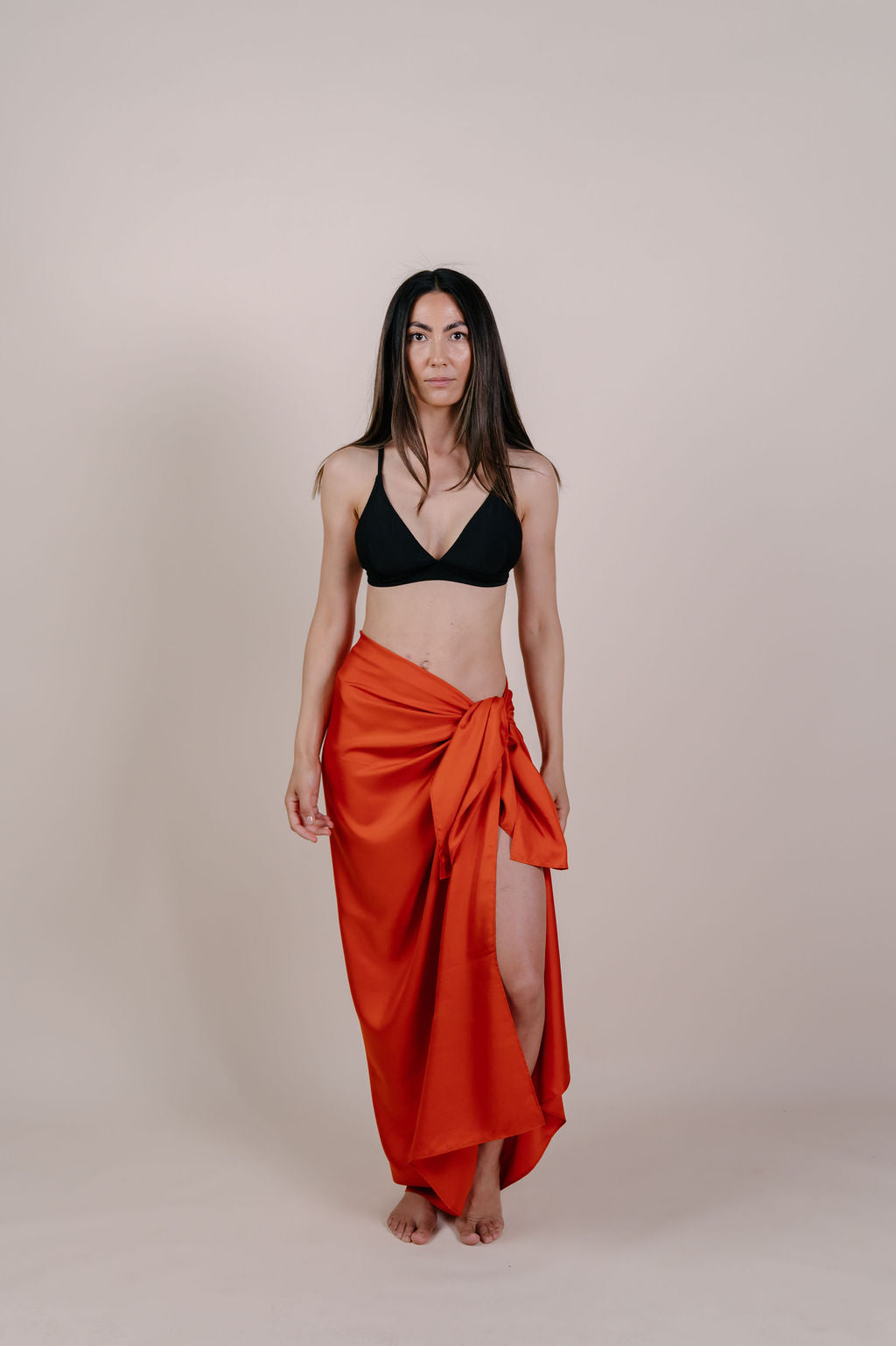 Model wearing the Luana solid terracotta silk pareo by Novo Pareo. Made from 100% Mulberry Silk Twill in warm terracotta, a timeless and versatile piece for refined Australian resort wear.
