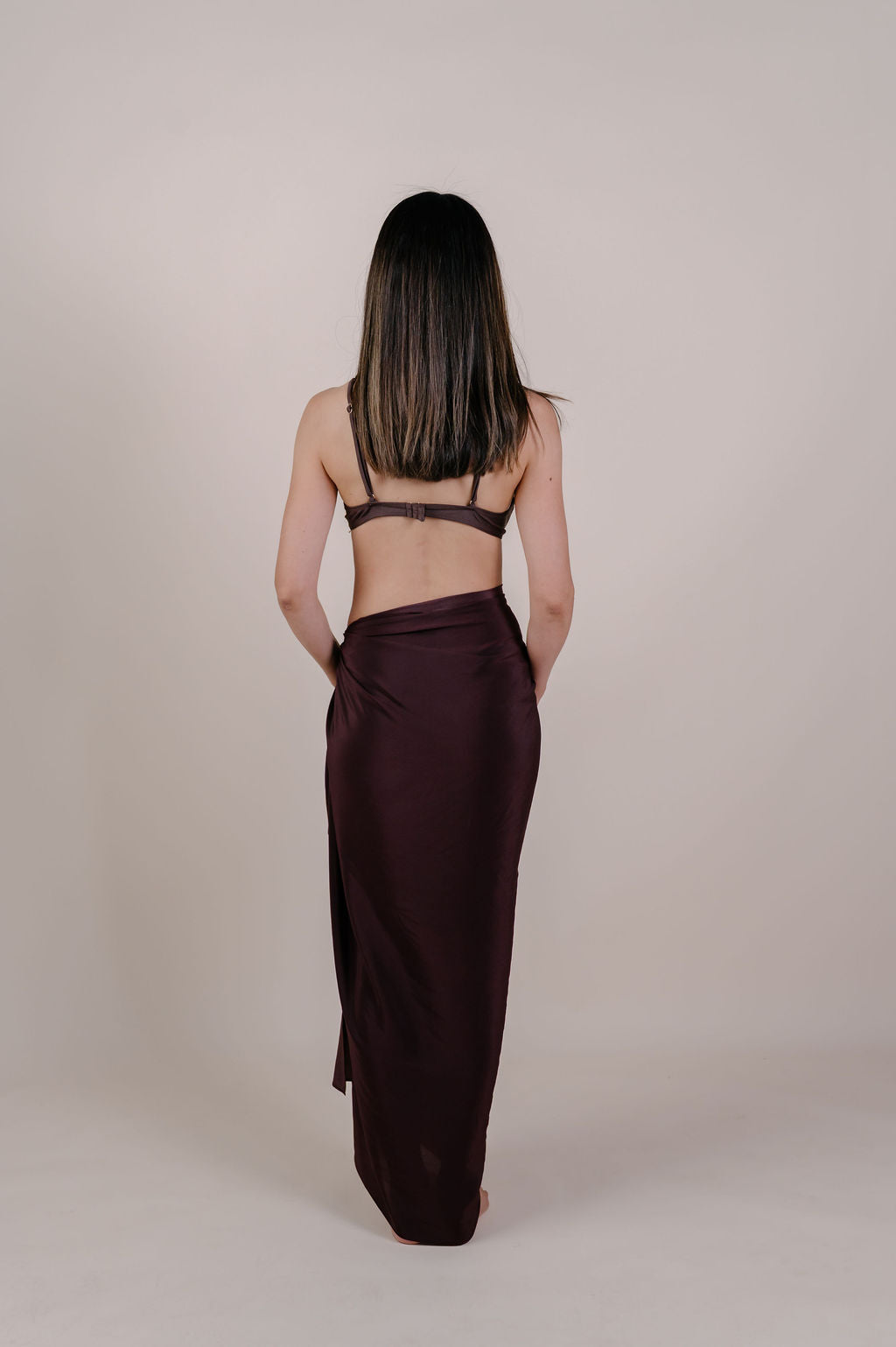 Model wearing the Noa solid chocolate silk pareo by Novo Pareo. 100% Mulberry Silk Twill in deep chocolate brown, minimalist and timeless design for refined Australian resort wear.