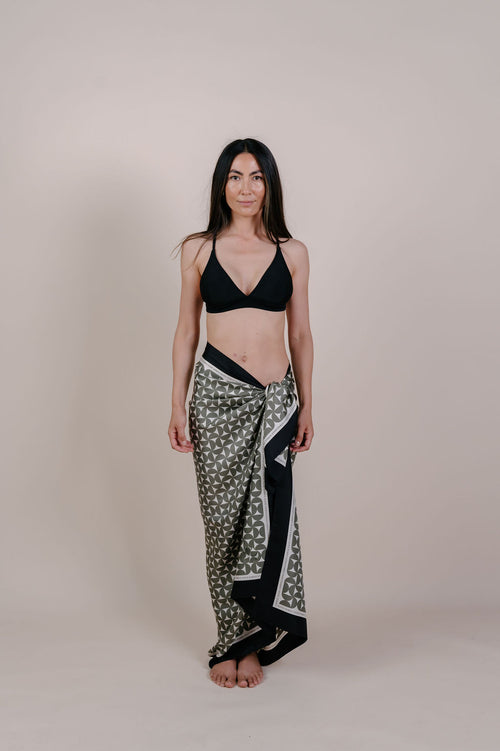 Model wearing the Solenne olive geometric silk pareo by Novo Pareo. 100% Mulberry Silk Twill with timeless geometric design and contrast border, created for refined Australian resort wear from beach to beyond.