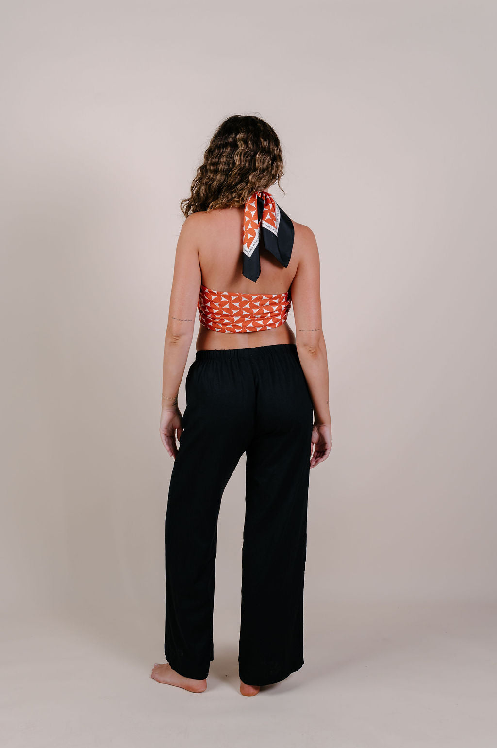 Model wearing the Sienna terracotta geometric silk pareo by Novo Pareo. 100% Mulberry Silk Crepe with bold terracotta print and contrast edge, designed in Australia for refined, timeless resort wear.