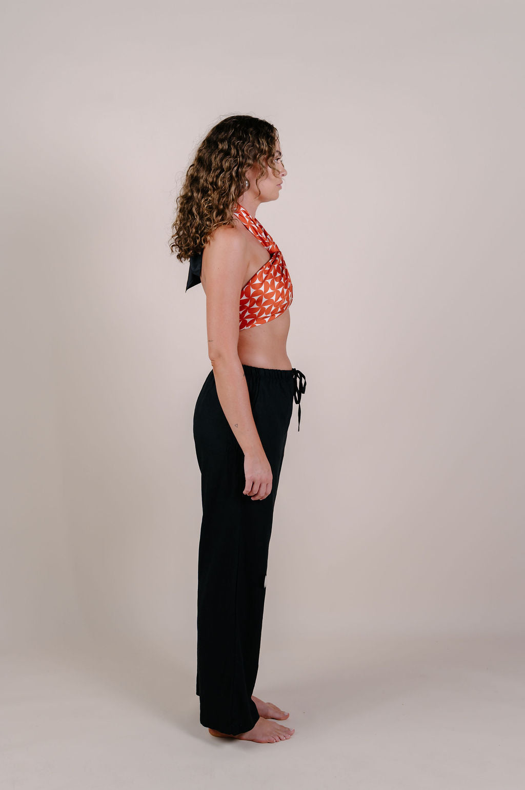 Model wearing the Sienna terracotta geometric silk pareo by Novo Pareo. 100% Mulberry Silk Crepe with bold terracotta print and contrast edge, designed in Australia for refined, timeless resort wear.