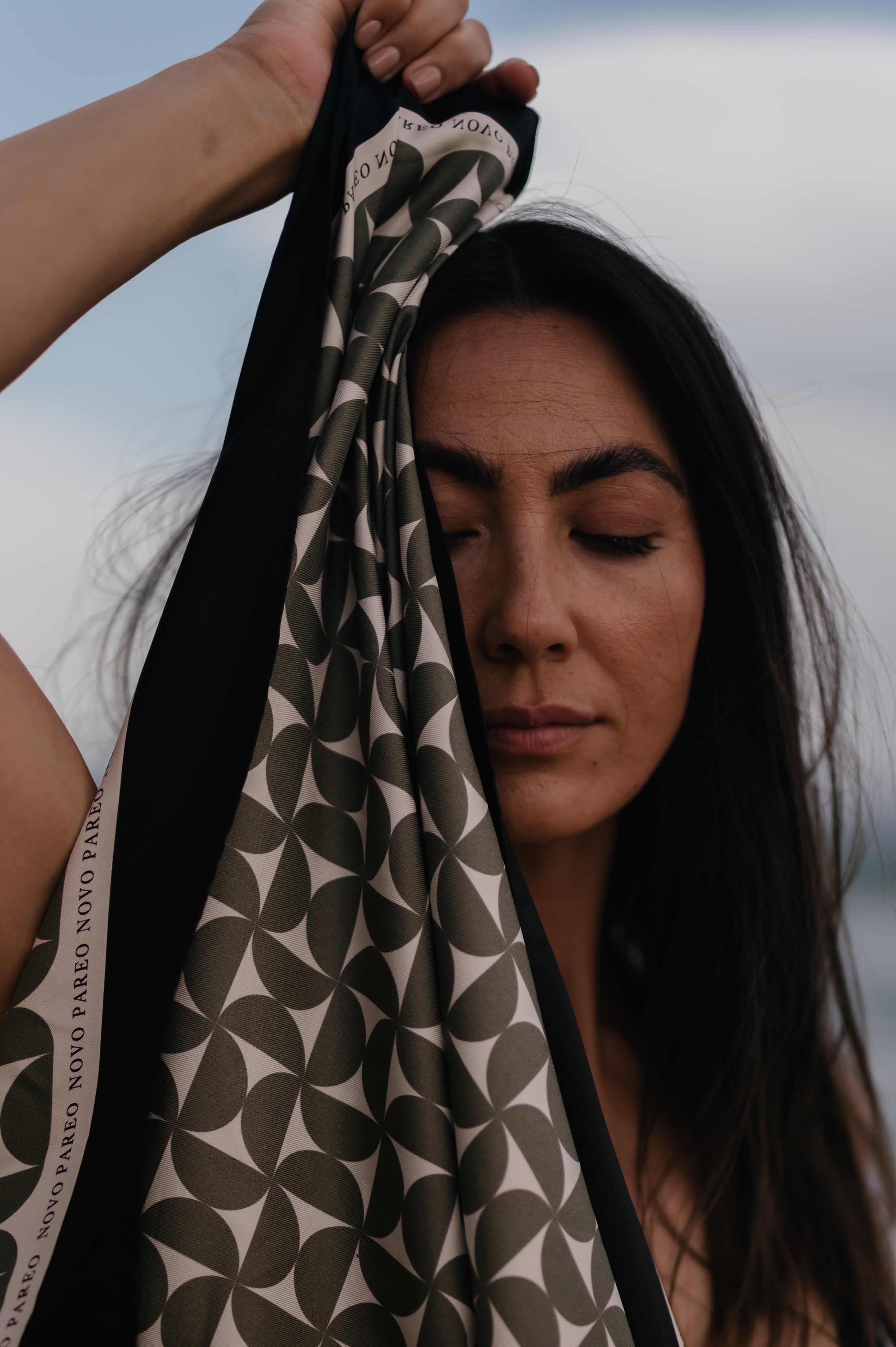 Woman holding a patterned pareo sarong with a blurred background